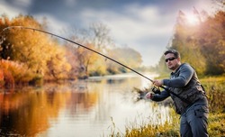 Fisherman having fight with a trophy fish on the river. Sport and recreation concept