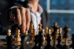 Business woman in a suit plays chess. Close-up of a female hand on a pawn