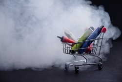 Disposable vapes in a shopping cart on a black background. Modern electronic cigarettes.