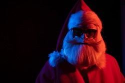 Santa claus in sunglasses in neon light on a black background. Christmas party.