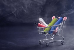 Disposable vapes in a shopping cart on a black background. Modern electronic cigarettes.