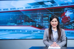 Beautiful Asian female news anchor in studio at broadcast room