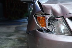 Golden brown car's front light is broken. Crashed car destroyed automobile part. Insurance of car crash is important