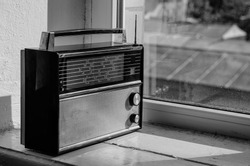 Vintage portable radio receiver standing on windowsill (black and white shot)