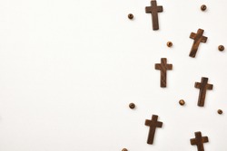 Background with wooden crosses and round beads arranged to the right on wooden table. Horizontal composition.