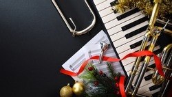 Christmas musical performance background with piano and trombone with christmas decoration, slider and mouthpiece. Top view.