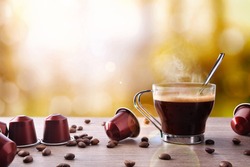Cup of coffee with capsules and beans and local background. Front view