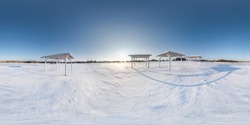 Winter full spherical seamless panorama 360 degrees angle view snow covered deserted beach with gazebos near lake  in snowy park with blue sky at evening in equirectangular projection. VR AR content