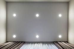 suspended ceiling with led diode spots lamps and drywall construction in empty room in apartment or house. Stretch ceiling white and complex shape.