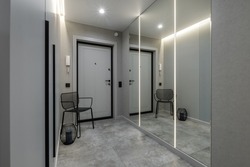 long corridor in interior of entrance hall of modern apartments with doors, cabinets, shelves and a mirror 