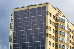 solar panels on the wall of a multi-storey building on storm clouds background. Renewable solar energy. an energy-efficient home that uses the energy of the earth, sun, air and wastewater