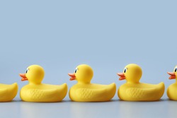 A side view of a row of rubber ducks on a blue background.