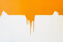 Orange paint drips on a white background, you can see the strokes from the brush that the man painted the wall, orange on white, wall renovation, art drawing, paint of bright color,flows down the wall