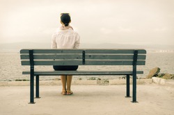 Lonely woman sitting on a bench by the sea
