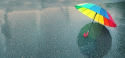 rainbow umbrella in puddle. natural background. colorful umbrella, symbol of rainy weather season. copy space. banner