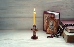 burning candle, orthodox icon, rosary beads, bible books on wooden table. concept of faith in God. Symbol of orthodox Church, lent, religion