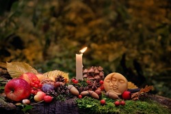 Moon amulet, candle, autumn leaves, fruits, berries, nuts in mysterious forest. Wiccan altar for Mabon sabbat. autumn equinox holiday. Witchcraft, esoteric spiritual ritual