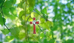 Christian cross with image of a dove on birch branches, abstract green natural background. symbol of Holy Spirit. Holy Trinity Sunday, festive Pentecost day. Faith in God, Church holiday concept