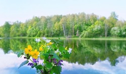 bouquet of wild flowers against blurred natural background of landscape with a river and forest. beautiful harmony peaceful nature floral image. spring summer season