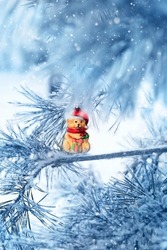 Teddy bear toy on snowy Christmas tree close up, winter abstract natural background. Christmas and new year holidays concept. winter festive season.