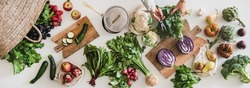 Fall vegetarian cooking background. Female hands cutting greens over table with fresh seasonal vegetables, greens, fruit from local grocery market, top view. Vegan, healthy, organic food