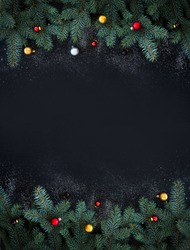 Christmas or New Year decoration background: fur-tree branches, colorful glass balls on black grunge background with copy space
