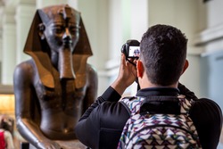 A tourist taking photo of an egyptian status brought from Egypt and kept in British Museum of London