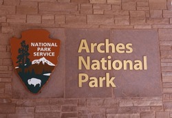 Arches National Park and National Park Service signs on the sandstone wall of the Visitor Center in Arches National Park, Moab, Utah, USA