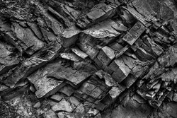 Texture, background layers and cracks in sedimentary rock on cliff face. Cliff of rock mountain. Rock slate in the mountain. Seamless abstract background. Cracks and layers of sandstone.