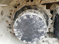 Detailed image of track pad and wheel components from underneath an earth mover.          