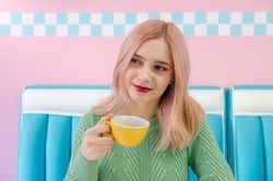 Girl with pink hair drinking tea in a cafe