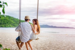 couple lover enjoy honeymoon and long vacation on the sea beach, siiting on the swing together relax and confortable, valentine occasion