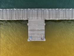 wooden bridge laying into lake at sunset shade in aerial view 