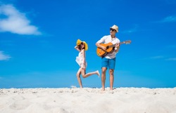 a happy and enjoy the trip honeymoon of couple lover on the sea beach by playing song music and jumping dance together at cleared blue sky daylight in background 
