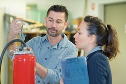 male professional checking the condition of a fire extinguisher