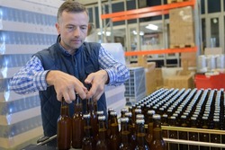 brewer holding beer bottles in crate at brewery