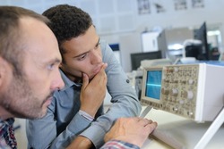 two men looking at radio frequency screen