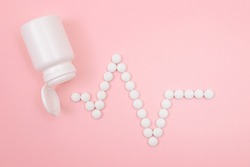 Heartbeat Rhythm. Electrocardiogram. ECG Line Made from White Pills Scattered from the Pill Container, Lying on Pink Background. Global Pharmaceutical Industry and Medicinal Products