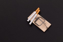 Tobacco Addiction and the World Corporation's Trap - Cigarettes in Wooden Mousetrap on Black Background