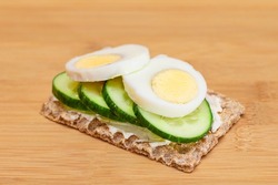 Whole Grain Crispbread with Fresh Cucumber, Egg, Cream Cheese and Radish on Bamboo Cutting Board. Easy Breakfast. Quick and Healthy Sandwiches. Crispbread with Tasty Filling. Healthy Dietary Snack