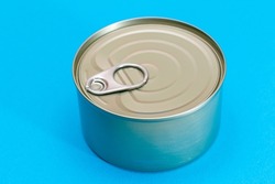 Unopened Tin Can with Blank Edge on Light Blue Background. Canned Food. Aluminum Can for Safe and Long Term Storage of Food. Steel Sealed Food Storage Container