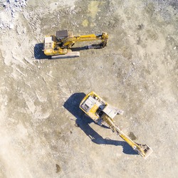 Aerial view of a working excavators on a construction site. Industrial background and heavy industry from above. 