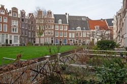 Begijnhof  is one of the oldest inner courts of Amsterdam with group of narrow historic houses in green garden, Netherlands. 