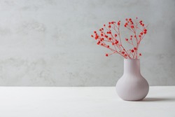 Small Bouquet of Red Flowers in Vintage Vase on White Table Grey Cement Wall Background. Styled Stock Image Mockup for Text Artwork Quotes Lettering Website Banner Template. Easter Mother's Day