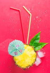 Creative Food. Conceptual Flat Lay Ripe Juicy Cut in Half Pineapple Green Leaves Drinking Straws Melting Ice Cubes Umbrella on Pink Background. Fresh Juices Summer Cocktails. Vacation Vitamins
