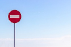 No entry for vehicular traffic. Road sign against blue sky. Space for text. A circular red sign with a white bar indicating 'NO ENTRY' on a grey metal post. road traffic signs.