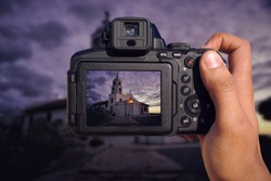 Camera in hand capturing historical landmark with dramatic sky in background
