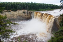 Unrecognizable people standing at the top of Alexandra Falls in the Northwest Territories, Canada, giving perspective as to the height of the falls
