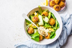 Vegan salad with beans meatballs, avocado and cucumber in white plate on a white background.