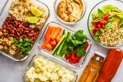 Healthy vegan food in glass containers, top view. Rice, beans, vegetables, hummus and juice for take-away lunch